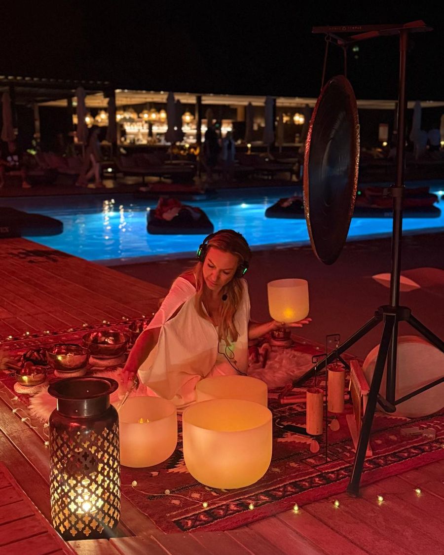 Vanessa Roux playing crystal bowls beside a hotel pool at dusk