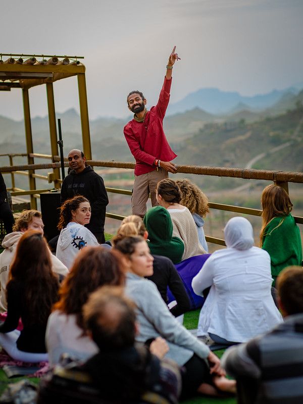 Manish Pole teaching a yoga class on a terrace above the mountains
